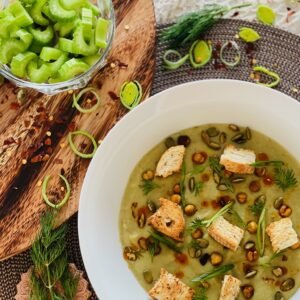 Decorated image of soup topped with croutons, chili oil, seeds, and slivered green onion.