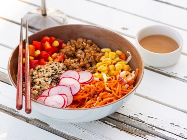 Sushi bowl with chop sticks and a BBQ aioli sauce in a side serving cup.